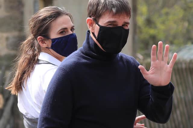 Actor Tom Cruise waves to onlookers as he walks to the set of his latest project, which is filming in the sidings of the railway station in the village of Levisham in the North York Moors.
