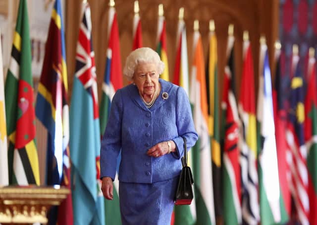 The Queen walking past Commonwealth flags in Windsor Castle.