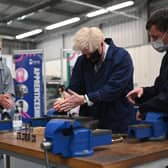 Britain's Prime Minister Boris Johnson (C) assists in an engine repair at the Automotive shop during a visit to Kirklees College Springfield Sixth Form Centre in Dewsbury, northern England on June 18, 2021. (Photo by Oli SCARFF / POOL / AFP) (Photo by OLI SCARFF/POOL/AFP via Getty Images)