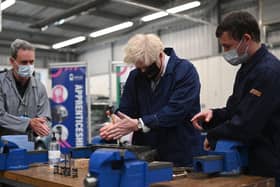 Britain's Prime Minister Boris Johnson (C) assists in an engine repair at the Automotive shop during a visit to Kirklees College Springfield Sixth Form Centre in Dewsbury, northern England on June 18, 2021. (Photo by Oli SCARFF / POOL / AFP) (Photo by OLI SCARFF/POOL/AFP via Getty Images)