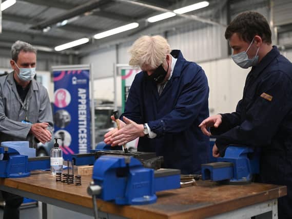 Britain's Prime Minister Boris Johnson (C) assists in an engine repair at the Automotive shop during a visit to Kirklees College Springfield Sixth Form Centre in Dewsbury, northern England on June 18, 2021. (Photo by Oli SCARFF / POOL / AFP) (Photo by OLI SCARFF/POOL/AFP via Getty Images)