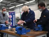 Britain's Prime Minister Boris Johnson (C) assists in an engine repair at the Automotive shop during a visit to Kirklees College Springfield Sixth Form Centre in Dewsbury, northern England on June 18, 2021. (Photo by Oli SCARFF / POOL / AFP) (Photo by OLI SCARFF/POOL/AFP via Getty Images)
