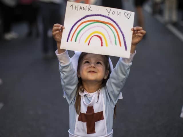 Maria Sole, four, dressed in a small nurses outfit holds up a rainbow drawing with the words 'Thank You' on it as NHS staff and members of the public take part in the weekly "Clap for Our Carers" event at Chelsea & Westminster Hospital on May 28, 2020 in London. Photo by Dan Kitwood/Getty Images.