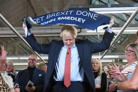 Prime Minister Boris Johnson holds up a banner with the words 'Get Brexit Done' during a visit to the John Smedley Mill, while election campaigning in Matlock, Derbyshire. Picture: Stefan Rousseau/PA Wire