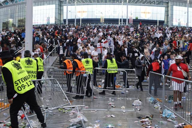 Stewards replace barricades after they were knocked over by supporters outside Wembley Stadium in London, Sunday, July 11, 2021. (AP Photo/David Cliff)