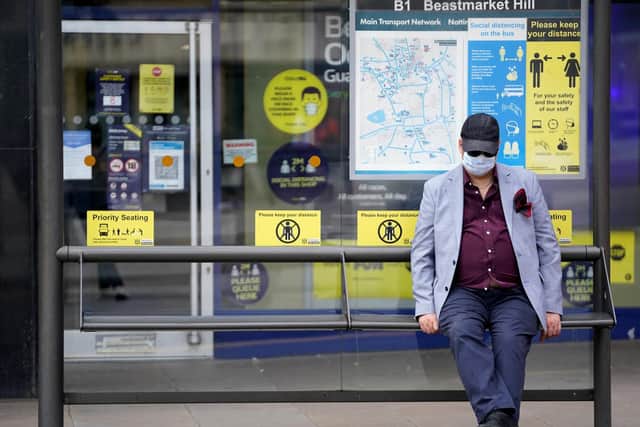 A member of the public wearing a mask sits at a bus stop during the easing of lockdown restrictions in England.