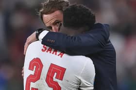 England's manager Gareth Southgate hugs  Bukayo Saka after the penalty shootout defeat at Wembley. (AP).