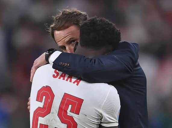 England's manager Gareth Southgate hugs  Bukayo Saka after the penalty shootout defeat at Wembley. (AP).