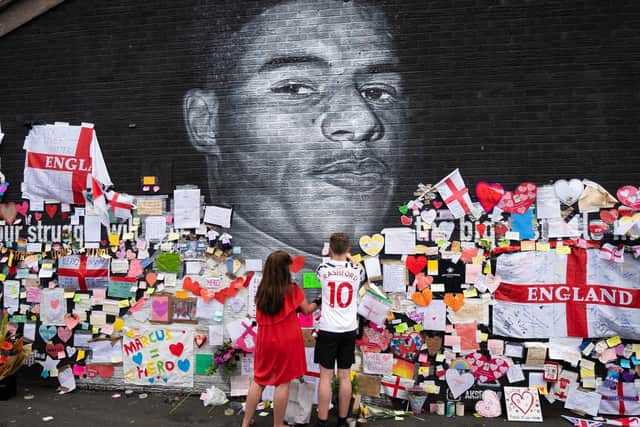 Mackenzie Robertson and his mother Sally Coles-Robertson put up a message on the mural of Manchester United striker and England player Marcus Rashford on the wall of the Coffee House Cafe on Copson Street, Withington. The mural appeared vandalised on Monday after the England football team lost the UEFA Euro 2021 final. Picture date: Tuesday July 13, 2021. Photo credit should read: Danny Lawson/PA Wire