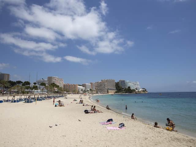 Tourists sunbathe at Magaluf Beach in Calvia, on the Balearic Island of Mallorca. British holidaymakers heading to the Balearic Islands will need to show a negative PCR test or proof of vaccination due to a rise in UK Covid infections, Spain said, reversing a free-entry policy. (Photo by JAIME REINA/AFP via Getty Images)