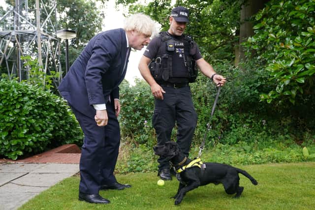 Prime Minister Boris Johnson speaks to Sergeant Dog Handler Mike Barnes as he throws a ball for six year old cocker spaniel Rebel, a proactive drugs dog, during a visit to Surrey Police headquarters in Guildford, Surrey, to coincide with the publication of the Government's Beating Crime Plan.