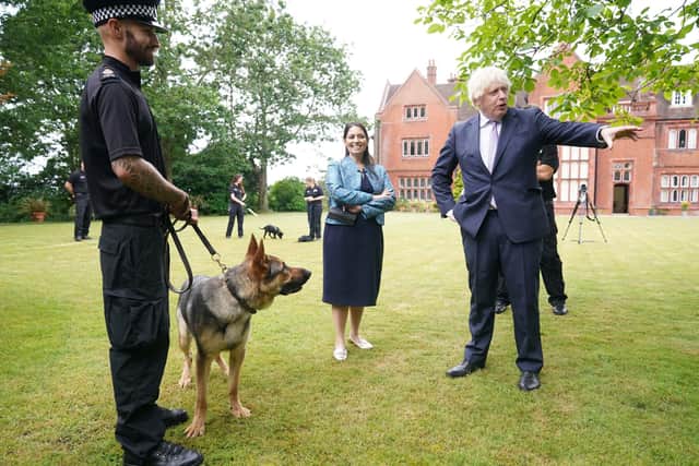 Prime Minister Boris Johnson, with Home Secretary Priti Patel, speaks to a police dog handler during a visit to Surrey Police headquarters in Guildford, Surrey, to coincide with the publication of the government's Beating Crime Plan.