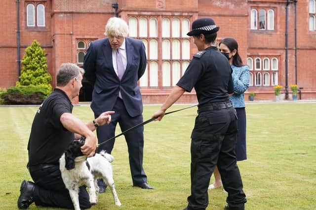 Prime Minister Boris Johnson, with Home Secretary Priti Patel, speaks to a police dog handler during a visit to Surrey Police headquarters in Guildford, Surrey, to coincide with the publication of the Government's Beating Crime Plan.