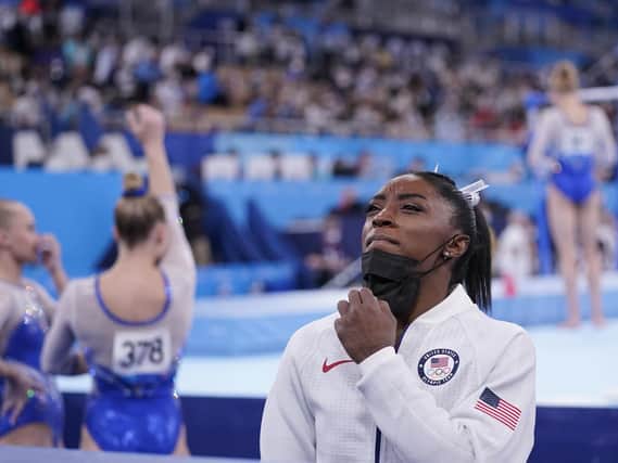 Simone Biles, of the United States, stands holding her mask after she exited the team final. (AP Photo/Gregory Bull)