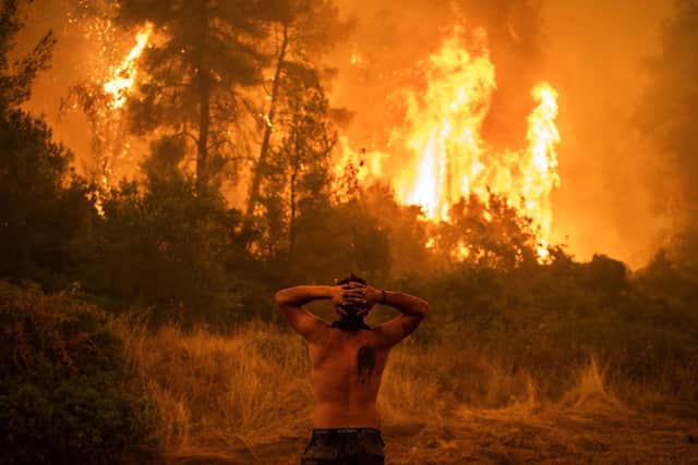 A local resident reacts as he observes a large blaze during an attempt to extinguish forest fires approaching the village of Pefki on Evia (Euboea) island, Greece's second largest island, on August 8, 2021. Greece and Turkey have been battling devastating fires for nearly two weeks as the region suffered its worst heatwave in decades, which experts have linked to climate change. (Photo by ANGELOS TZORTZINIS / AFP)