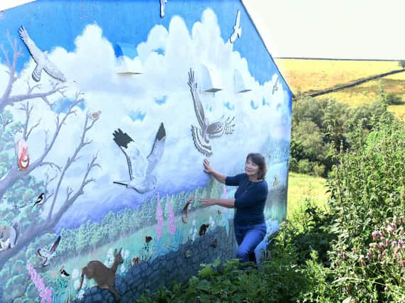 Nicky Johnson beside the mural, which overlooks a public footpath and bridleway