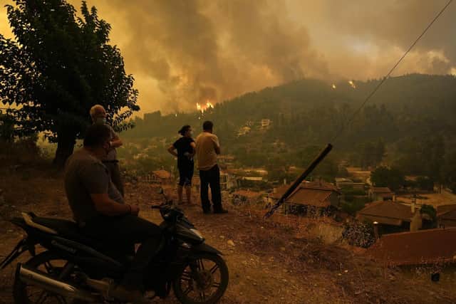Piers Torday says it is important to tell the children the truth about events like recent wildfires in Greece. The picture shows local residents standing on a hill as flames approaching at Gouves village on the island of Evia, about 185 kilometers (115 miles) north of Athens, Greece, Sunday, Aug. 8, 2021. AP Photo/Petros Karadjias)