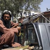 A Taliban fighter sits on the back of vehicle with a machine gun in front of the main gate leading to the Afghan presidential palace, in Kabul, Afghanistan, Monday, Aug. 16, 2021. The U.S. military has taken over Afghanistan's airspace as it struggles to manage a chaotic evacuation after the Taliban rolled into the capital. (AP Photo/Rahmat Gul).