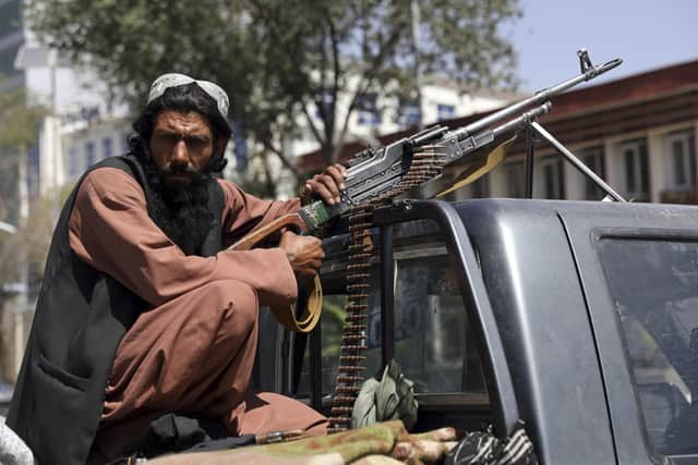 A Taliban fighter sits on the back of vehicle with a machine gun in front of the main gate leading to the Afghan presidential palace, in Kabul, Afghanistan, Monday, Aug. 16, 2021. The U.S. military has taken over Afghanistan's airspace as it struggles to manage a chaotic evacuation after the Taliban rolled into the capital. (AP Photo/Rahmat Gul).