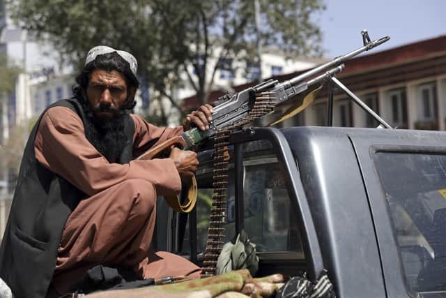 A Taliban fighter sits on the back of vehicle with a machine gun in front of the main gate leading to the Afghan presidential palace, in Kabul, Afghanistan, Monday, Aug. 16, 2021. The U.S. military has taken over Afghanistan's airspace as it struggles to manage a chaotic evacuation after the Taliban rolled into the capital.