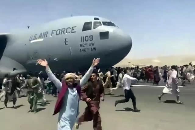 Hundreds of people run alongside a U.S. Air Force C-17 transport plane as it moves down a runway of the international airport, in Kabul, Afghanistan.