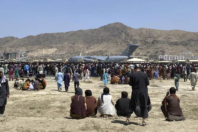 Hundreds of people gather near a U.S. Air Force C-17 transport plane at a perimeter at the international airport in Kabul, Afghanistan.