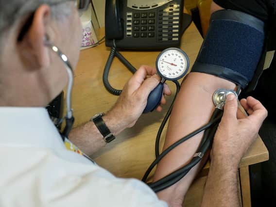 File photo dated 10/09/14 of a GP checking a patient's blood pressure. (PA/Anthony Devlin)