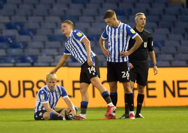 Sheffield Wednesday's Sam Hutchinson lays out injured consoled by team-mates George Byers and Lewis Wing   Picture: Steve Ellis