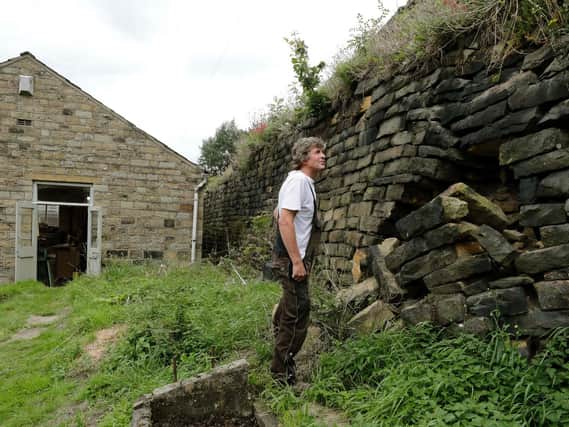 Ivan Beardsell beside the crumbling drystone wall in Holmfirth