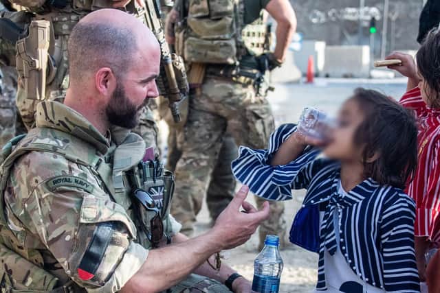 Handout photo issued by the Ministry of Defence (MoD) of Lt Cdr Alex Pelham Burns, a member of the UK Armed Forces who continue to take part in the evacuation of entitled personnel from Kabul airport, offering water to a child. Issue date: Monday August 23, 2021.
