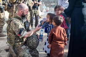 Handout photo issued by the Ministry of Defence (MoD) of Lt Cdr Alex Pelham Burns, a member of the UK Armed Forces who continue to take part in the evacuation of entitled personnel from Kabul airport, offering water to a child. Issue date: Monday August 23, 2021.