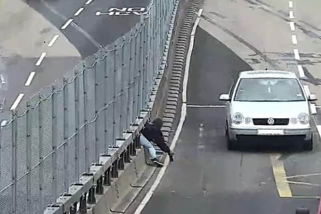 The pedestrian clambers through a hole in the barrier and into oncoming traffic