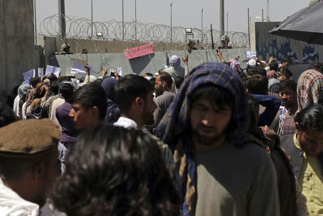 U.S. soldiers stand inside the airport as hundreds of people gather some holding documents, near an evacuation control checkpoint on the perimeter of the Hamid Karzai International Airport, in Kabul, Afghanistan, Thursday, Aug. 26, 2021.  (AP Photo/Wali Sabawoon)