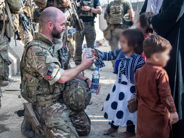 Lt Cdr Alex Pelham Burns offering water to a child during the Afghanistan evacuation effort. Picture: LPhot Ben Shread/MoD/PA Wire
