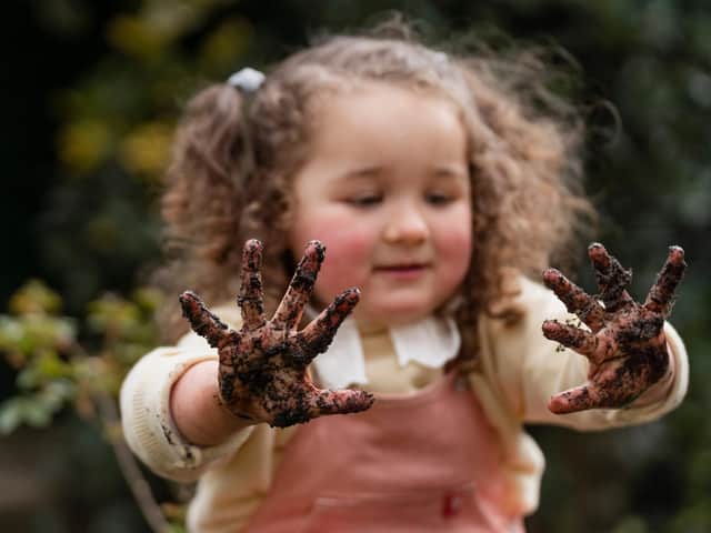 A little girl with muddy hands enjoys gardening activities in the garden. Credit Line RHS / Georgi Mabee