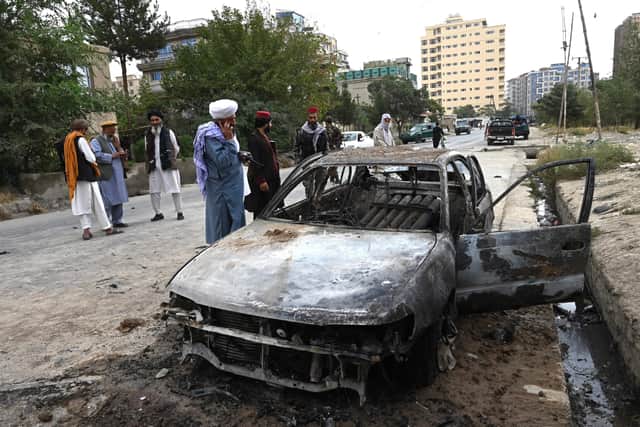 Taliban fighters investigate a damaged car after multiple rockets were fired in Kabul on August 30, 2021. - Rockets flew across the Afghan capital on August 30 as the US raced to complete its withdrawal from Afghanistan.