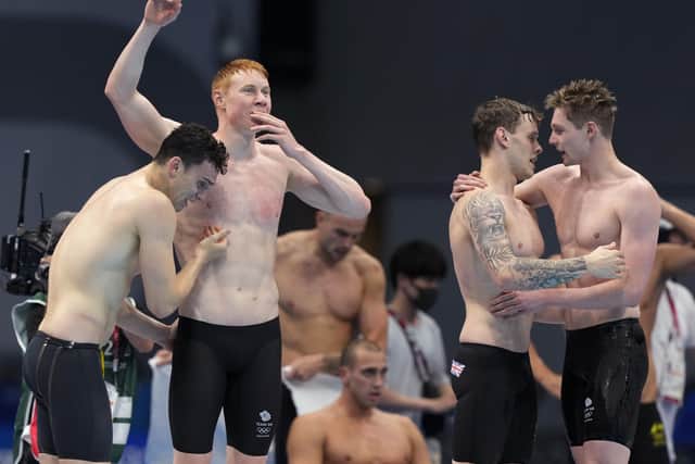 Britain's men's 4x200-meters relay team Tom Dean, James Guy, Matthew Richards, and Duncan Scott celebrate after winning the gold medal at the 2020 Summer Olympics.