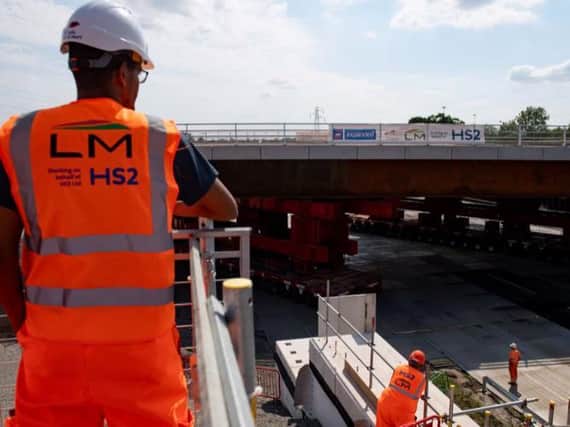 HS2 workers watch as a bridge is wheeled into position over the M42 at the HS2 Interchange station site near Solihull