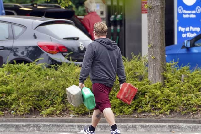 A man carrying containers at a Tesco petrol station