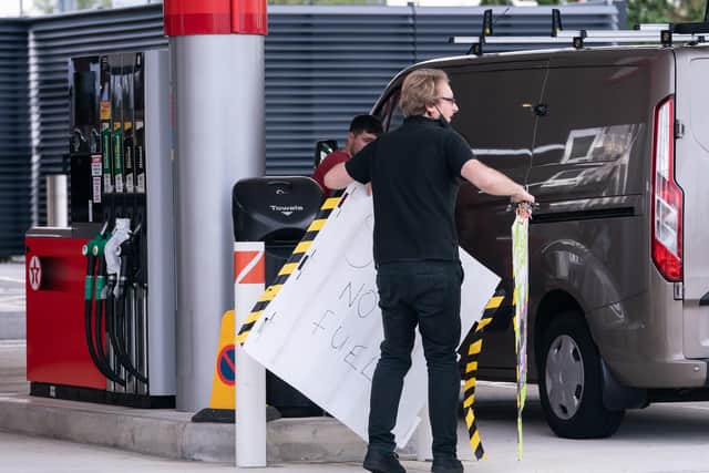 An employee removes a no fuel sign from the  forecourt of a petrol station in Leeds.