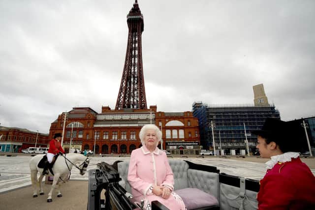 The wax figure of Queen Elizabeth II is driven in a horse and carriage along the seafront in Blackpool