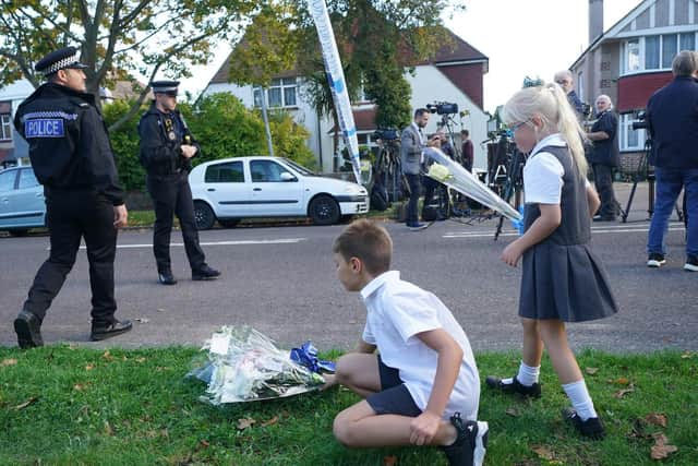 Children leave flowers at the scene near the Belfairs Methodist Church in Eastwood Road North, Leigh-on-Sea, Essex, where Conservative MP Sir David Amess has died after he was stabbed several times at a constituency surgery.