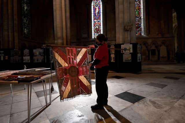 Regimental Flags are lowered in the Regimental Chapel at Beverley Minster.. Virger Libby Naylor Holding one of the flags. Image Simon Hulme