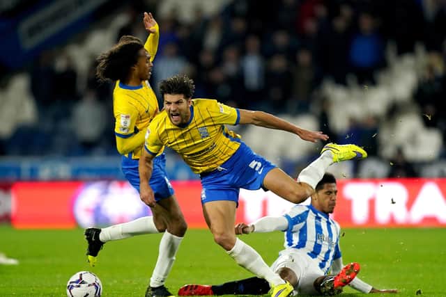 Birmingham City's George Friend is tackled by Huddersfield Town's Levi Colwill.