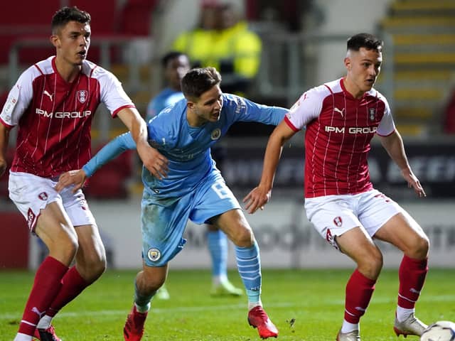 Manchester City's James McAtee (centre) and Rotherham United's Jacob Gratton (right) battle for the ball (Picture: PA)