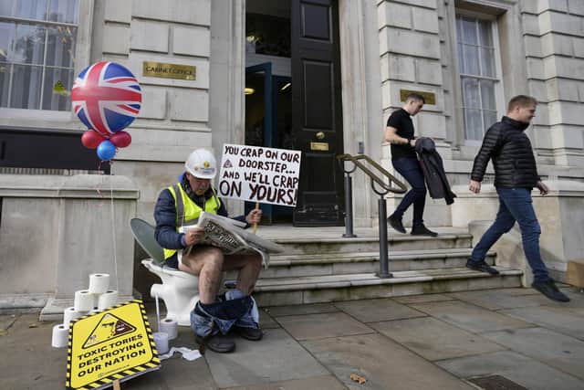 An activist sits on a toilet at the entrance to Downimng Street to protest against raw sewage dumping in the rivers and seas around the UK after leaving the EU