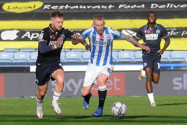 Huddersfield Town's Lewis O'Brien is challenged by Millwall player Tom Bradshaw.