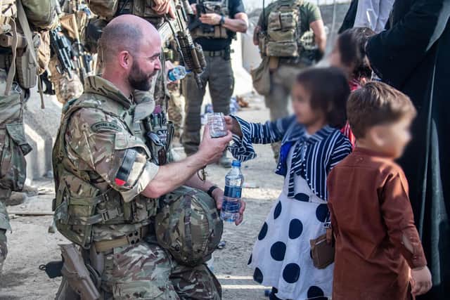 .Handout photo issued by the Ministry of Defence (MoD) of Lt Cdr Alex Pelham Burns, a member of the UK Armed Forces who took part in the evacuation of entitled personnel from Kabul Airport, offering water to a child.