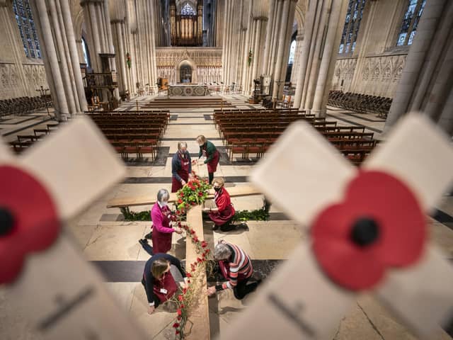 Flower arrangers add the finishing touches to a large cross being decorated with poppies at York Minster ahead of the cathedral's services to mark Armistice Day and Remembrance Sunday.