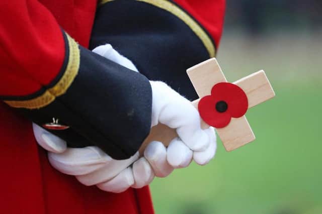 A veteran holding a cross bearing a poppy